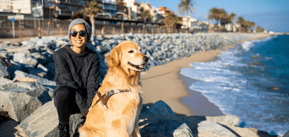 María junto a su perro guía Tavish frente al mar
